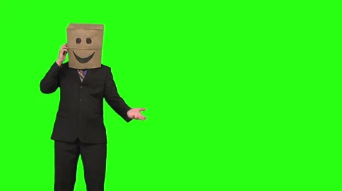 Paperbag man using a cellphone. wide shot. green background Stock Footage 49863328