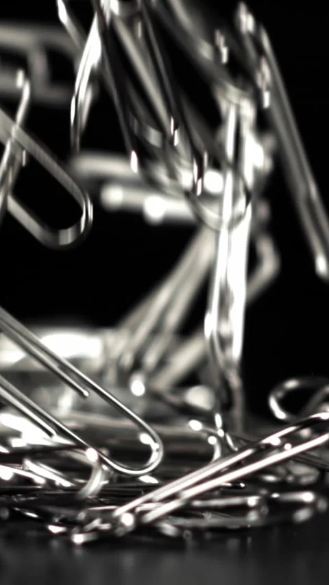 Paperclips fall on a black background. Filmed on a high-speed camera at 1000 fps Stock Footage 335379270