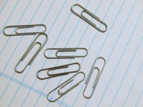 Paperclips lying on lined paper Stock Photos