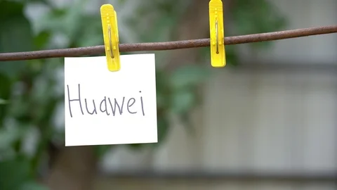 Papers with words Huawei and IPhone hanging on rod. Man hand hang word on right. Stock Footage 108773231