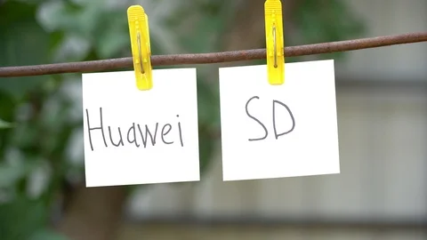 Papers with the words Huawei and SD on yellow clothespins hanging on rod. Stock Footage 108773580