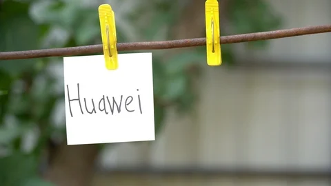 Papers with words Huawei and SD hanging on rod. Man hand hang word on right. Stock Footage 108773587