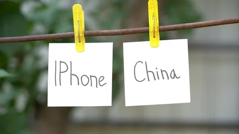 Papers with the words Iphone and China on yellow clothespins hanging on rod. Stock Footage 108774545
