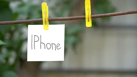 Papers with words IPhone and Google hanging on rod. Man hand hang word on right. Stock Footage 108774654