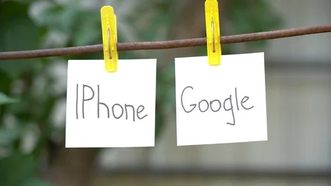 Papers with the words Iphone and Google on yellow clothespins hanging on rod. Video stock 108774686