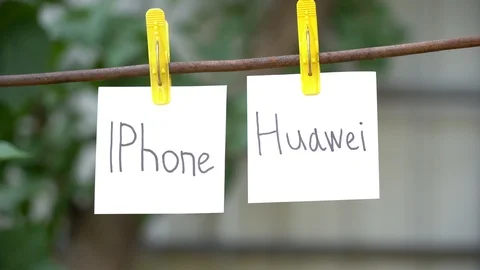 Papers with the words Iphone and Huawei hanging on metal rod. The concept war. Stock Footage 108773862