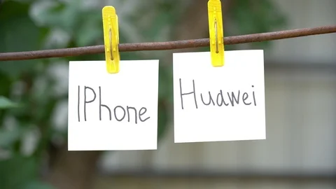 Papers with words IPhone and Huawei on rod. Man hand take away word on right. Stock Footage 108773970
