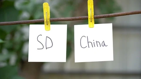 Papers with words SD and China on rope. Man hand take away word on right. Stock Footage 108775219