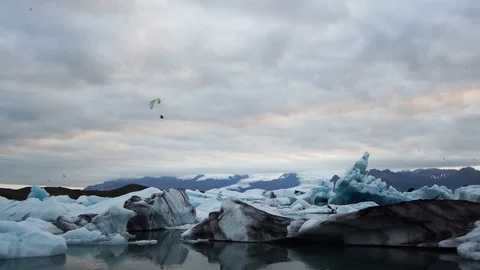Para glider flying low over glacier lagoon full of icebergs in evening Video stock 93675807