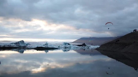 Para glider flying low over glacier lagoon full of icebergs in evening Video stock 93675887