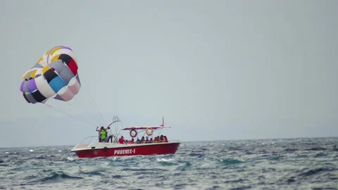 Para gliding sailing behind power speed boat floating against cloudy sky at Stock Footage 172210168