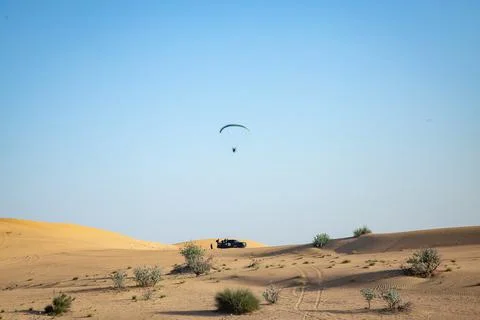 Para plane flying over sandy dunes on background of the clear blue sky 写真素材