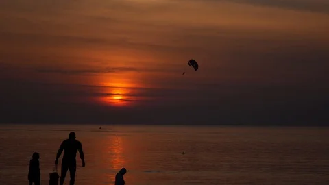 Parachute activity at tropical beach at sunset. Silhouettes of people walking on Video stock 108199449