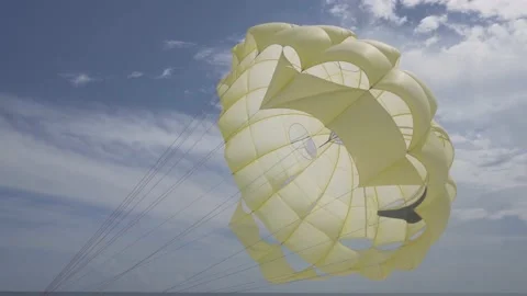 Parachute flying in wind with blue sky at Seaside. Yellow parachute opened Stock Footage 131236141