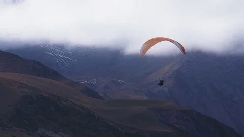 Parachute gliding through mountains Stockbeeldmateriaal 172046139