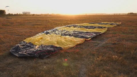 Parachute lying on the ground in the sunset rays of the sun on the airfield Stock Footage