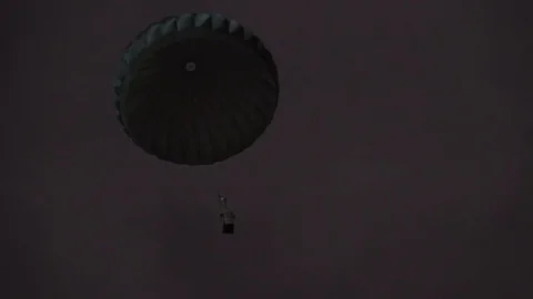 Parachute package coming down from the sky at night Stock Footage 113343646