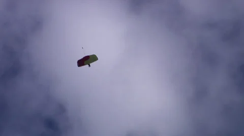 Parachuter from ground, against clouds, with snapzoom out Stock Footage 24676010