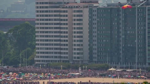 Parachutist landing on crowded beach during airshow Vidéo 336254599