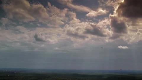 Parachutists is flying down with sun rays passing through clouds on background Stock Footage 159555341