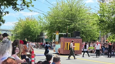 Parade float shaped like a brick house with performers Video stock 339116559
