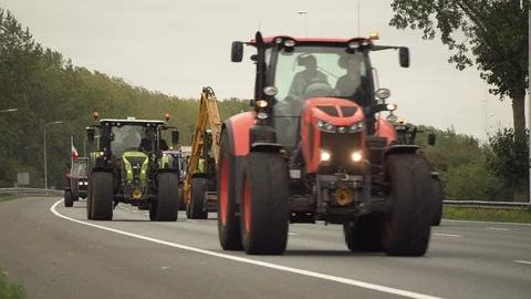 Parade of tractors driving side by side on highway causing slow traffic Stock Footage 130132196