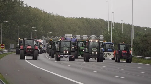 Parade of tractors driving side by side on highway causing slow traffic Stock Footage 130134938