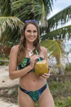 Paradise Found: Stunning Model Sips Cocoanut by Caribbean Shore in Bikini Bli Stock-Fotos
