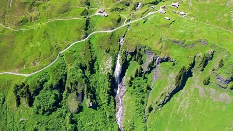 Paradise like waterfall surrounded by green meadows in the Alps of Switzerland Stock Footage 246984016