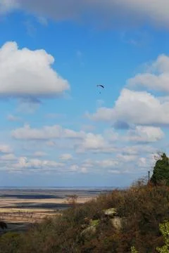 Paraglider in the blue cloudy sky with fields in the background 库存照片