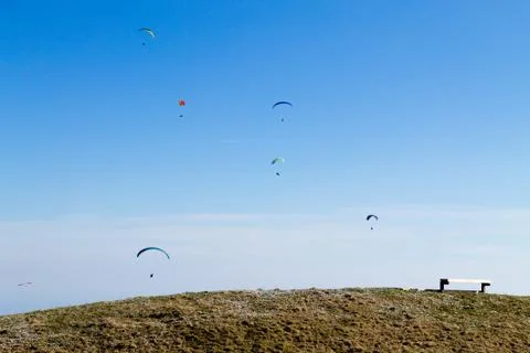 Paraglider on blue sky with empty bench on foreground Fotos de archivo