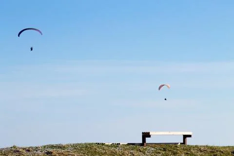 Paraglider on blue sky with empty bench on foreground Fotos de archivo