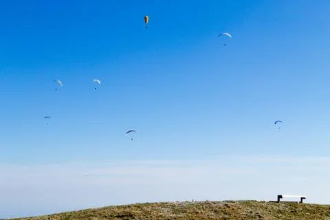 Paraglider on blue sky with empty bench on foreground Fotos de archivo