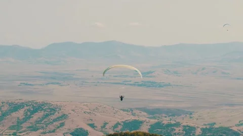 Paraglider calmly soaring through the air with his glider while other Video stock 266258219