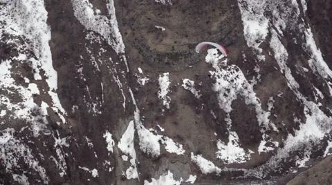 Paraglider coming down against the background of snow covered rocks Stock Footage 65955352
