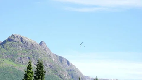 Paraglider descends from the sky, making continuous turns among mountains Stock Footage 330259793