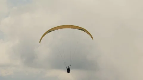 The paraglider flies in the clouds over the mountains on a cloudy day. Extreme Stock Footage 107854985
