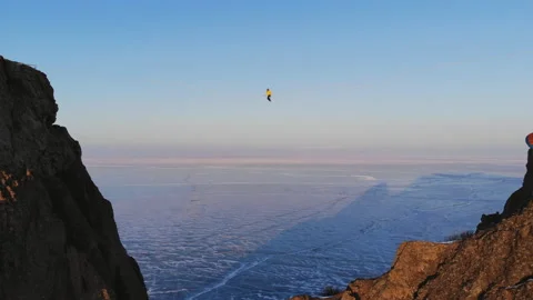 Paraglider flies gracefully under the bridge on which the woman sits. Stock Footage 110943588