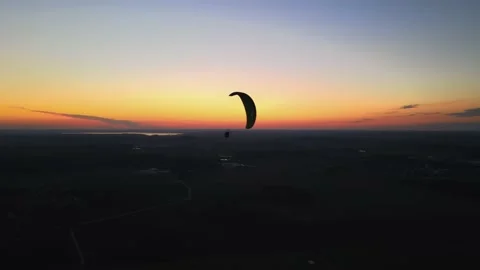 A paraglider flies at sunset over the plains Stock Footage 196136046