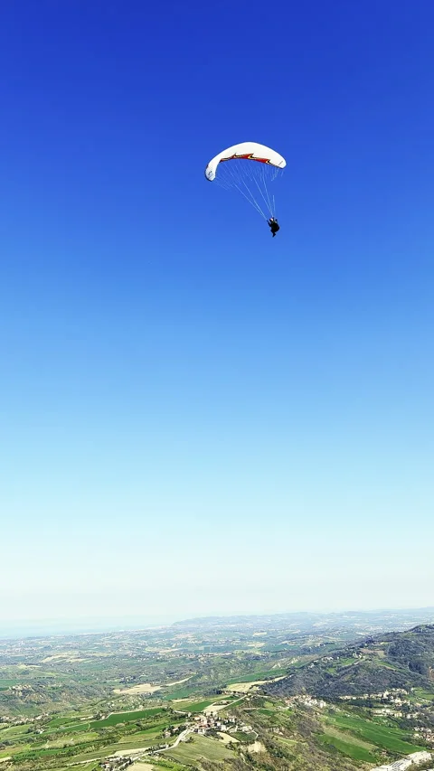 Paraglider in flight against a vast panoramic landscape of hills and vineyards Vídeo Stock 333604929