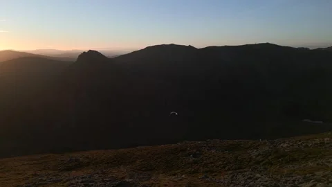 A paraglider floating through the sky in the mountains at sunrise Stock Footage 246742278
