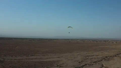 A paraglider floats over the Mojave Desert landscape at dusk with a scenic Stock Footage 190824600