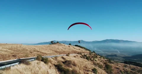 Paraglider fly gliding over mountain landscape with clear blue skies Stock Footage 312096841