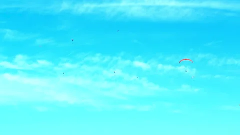 Paraglider flying high above clouds in a vibrant blue sky. 库存影片 330606725