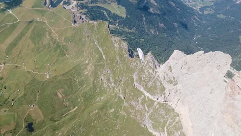 Paraglider Flying Near The Rugged Cliffs And Green Slopes Of The Dolomites In 库存影片 345165558