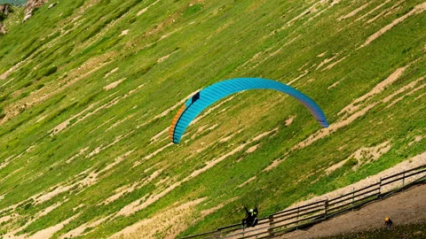 Paraglider flying over green mountain slope near Almaty Stock Footage 334921553