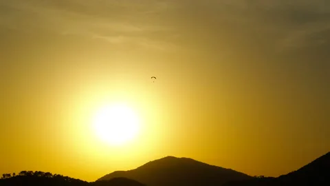 Paraglider flying over mountain during golden hour sunset 動画素材 320050659
