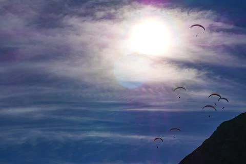 Paraglider flying over mountains in summer day in front of the mountain Foto stock