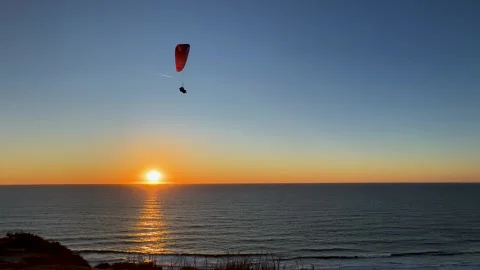 Paraglider flying a red glider across a beautiful clear sunset at Torrey Stock Footage 266229286