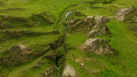 Paraglider follows mountain stream through lush mountainous terrain, aerial Video stock 260887654
